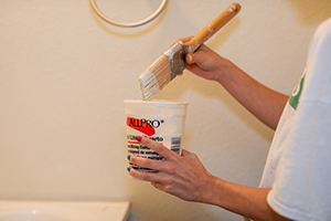 person dipping paint brush in paint